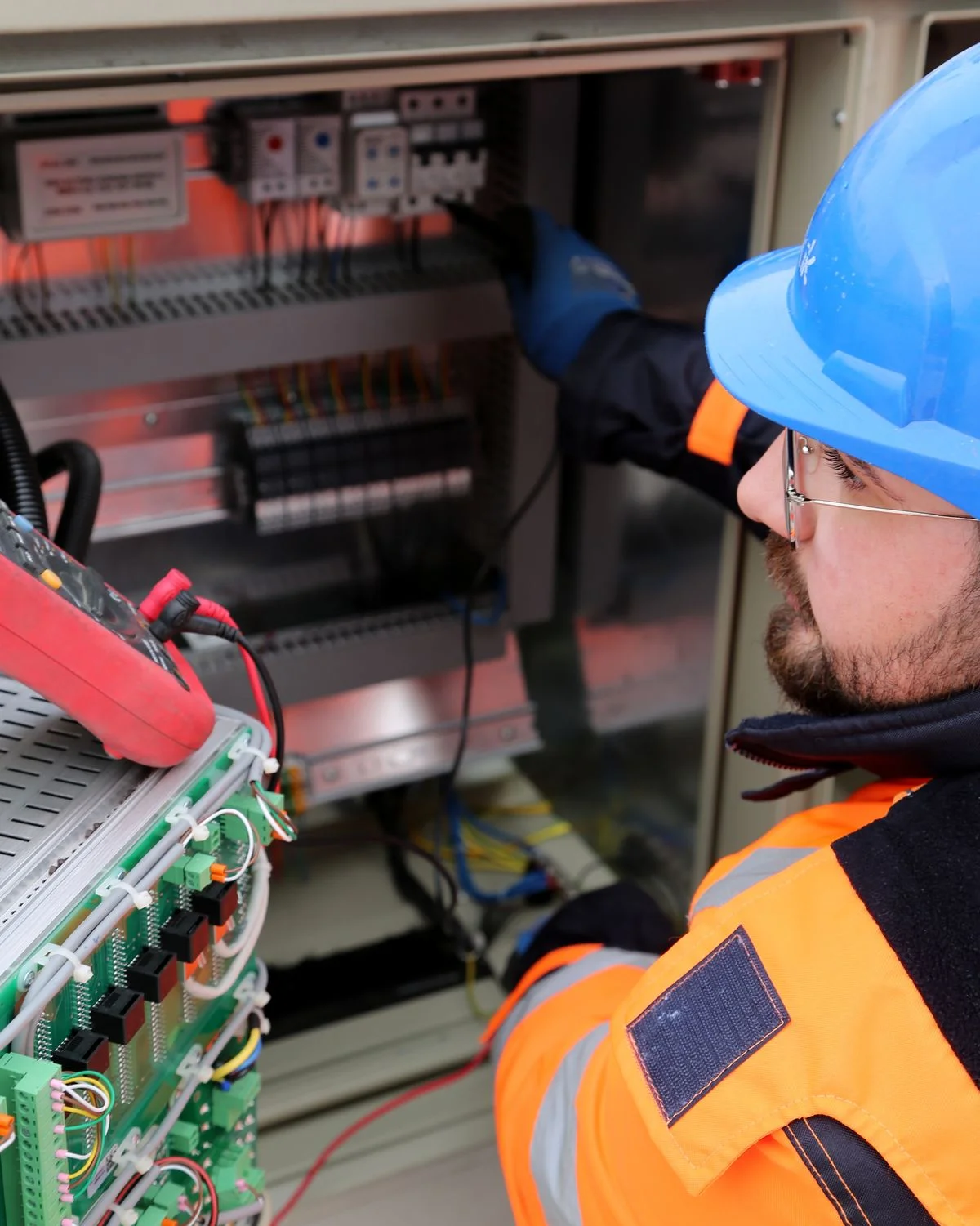 Electricista con casco inspeccionando tablero eléctrico industrial